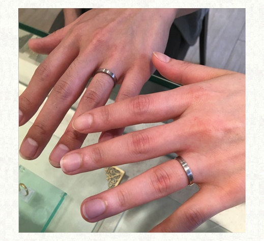 白とグレーのモノトーンデザインの結婚指輪　お客様の指にリングをつけて