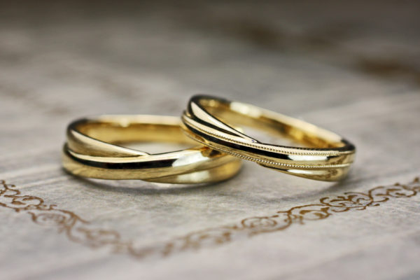 センターでクロスしたデザインのゴールドの結婚指輪