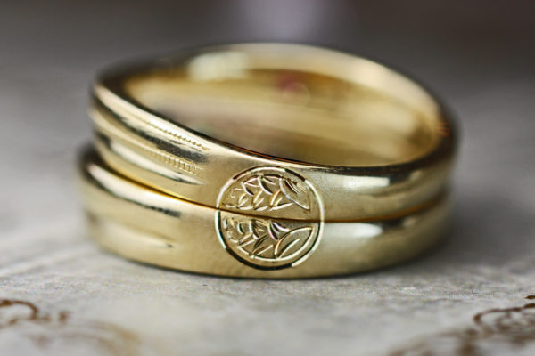 結婚指輪を重ねて両家の家紋を作りあげるゴールドのペアリング