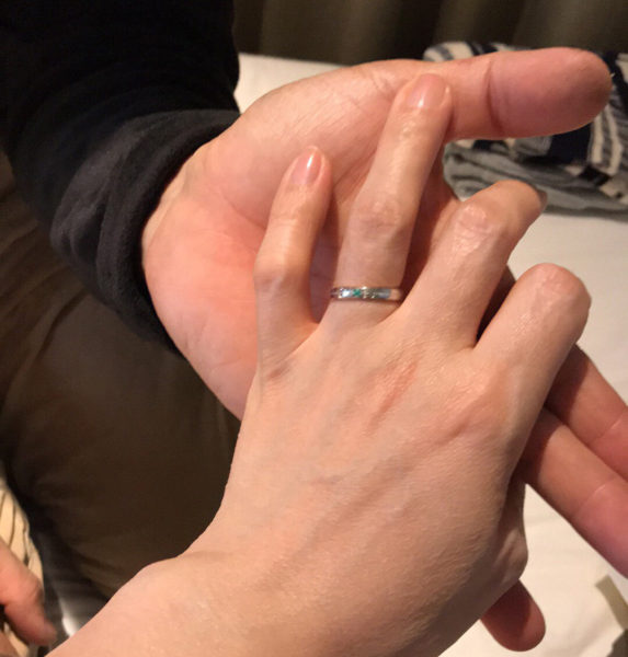 パライバトルマリンと模様を入れたオーダー結婚指輪を指につけたお客様