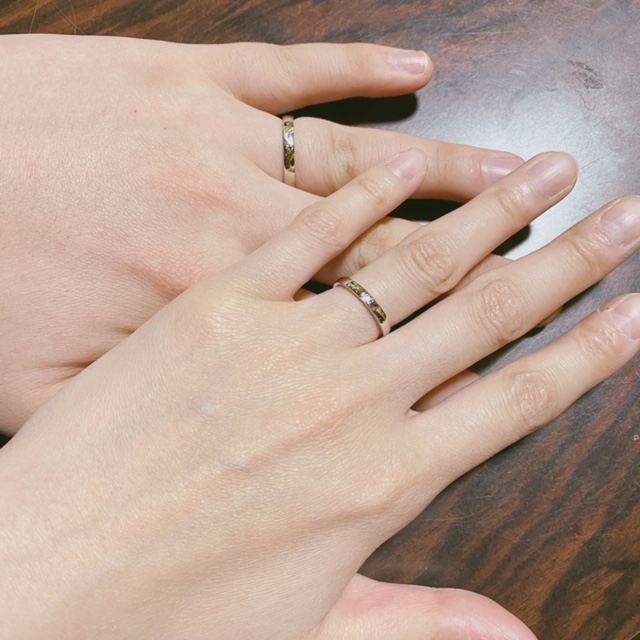 2本重ねて月とサクラ草で飾られた模様をつくる結婚指輪を薬指につけたお客様の手の画像